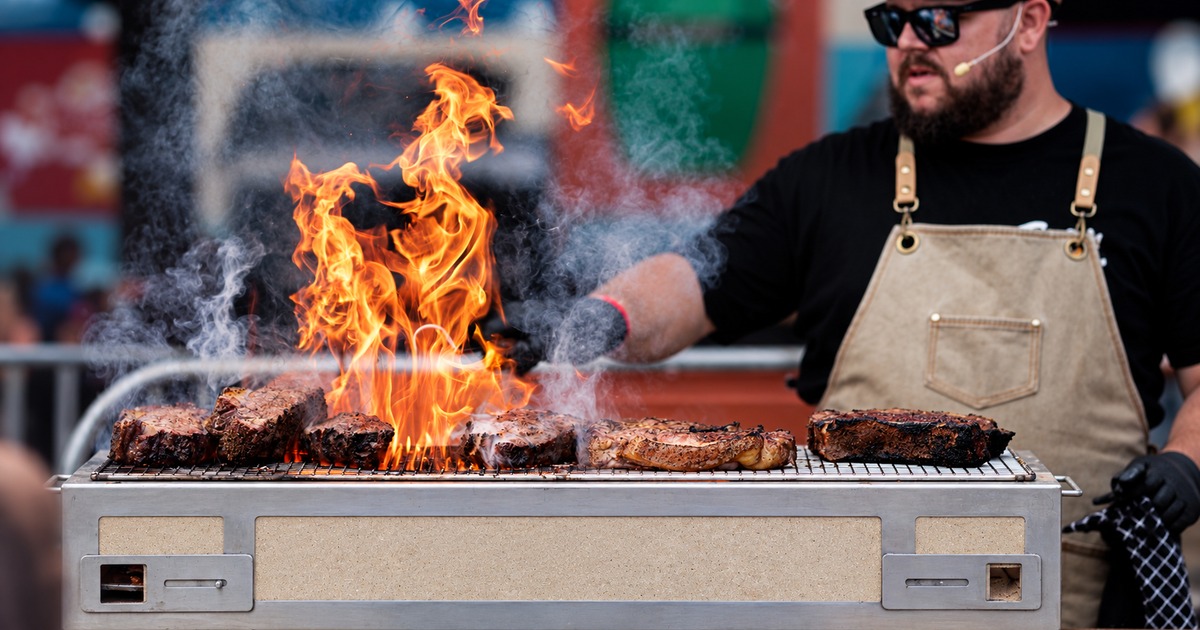 Promotional photograph of a cook grilling steaks, adapted from SizzleFest’s 2026 image; not a record of 2027.